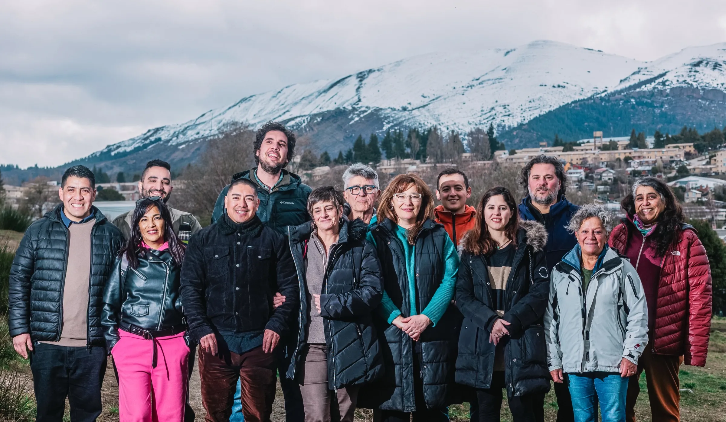 Las candidatas y los candidatos de Fuerza Bariloche, al aire libre, con el cerro nevado y la ciudad de Bariloche de fondo.